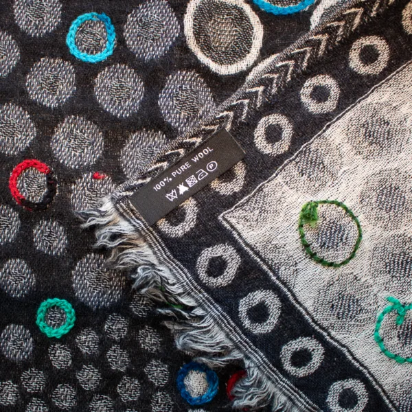 Detailbild. Wunderschöner Schal, 100 % Wolle, schwarz-weiß, mit eingewebten Punkten, bunt bestickt.