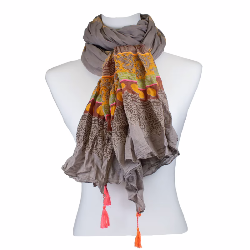 Schal in taupe- und graufarbenem Grundton mit längs verlaufenden Linien in Gelb. Untere Bereiche mit ornamentalen Bordüren in Orange, Rot und Gelb. Punktmotive innerhalb der Bordüren sichtbar. Unterschiedlich strukturierte Musterzonen entlang der Länge. Abschlüsse mit farbigen Quasten in Pink und Orange.