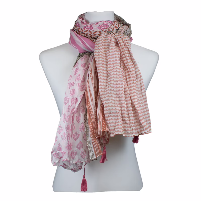 Mehrfarbiger Schal mit unterschiedlichen Musterfeldern in Rosa, Creme und Grau. Kombination aus schmalen Längsstreifen, feinen Punktmustern und grafischen Flächen. Horizontal gegliederte Abschnitte mit Farbwechseln. Sichtbare Quasten in Korallton an den Enden.