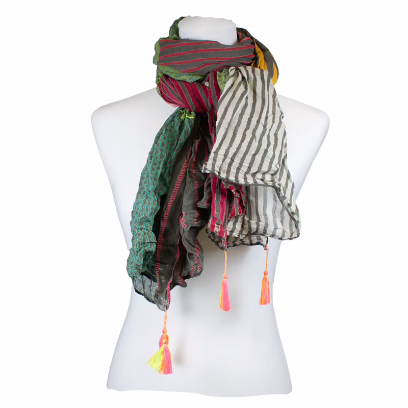 Mehrfarbiger Schal mit klar gegliederten Farb- und Musterflächen. Kombination aus längs verlaufenden Streifen in Blau und Grün, feinen Linien in Grau sowie ornamentalen Motiven in Pink und Rot. Unterschiedlich farbige Felder entlang der Länge angeordnet. Abschlüsse mit sichtbaren Quasten in Pink und Gelb.