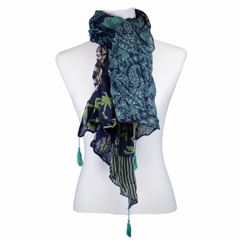 Mehrfarbiger Schal mit dunkelblauem Grundton und klar gegliederten Musterflächen. Kombination aus floralen Ornamenten, kleinen grafischen Motiven und schmalen Streifen in Blau, Grün und Weiß. Unterschiedliche Musterzonen längs angeordnet. Abschlüsse mit sichtbaren Quasten in Grün.