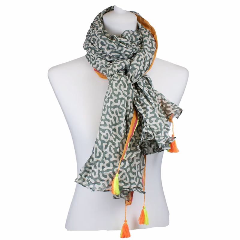 Schal mit dichtem Allovermuster in Oliv und Weiß. Kleine, gleichmäßig verteilte grafische Ornamente über die gesamte Fläche. Schmale, seitliche Randstreifen in Koralle und Gelb sichtbar. Abschlüsse mit farbigen Quasten in Gelb und Pink.