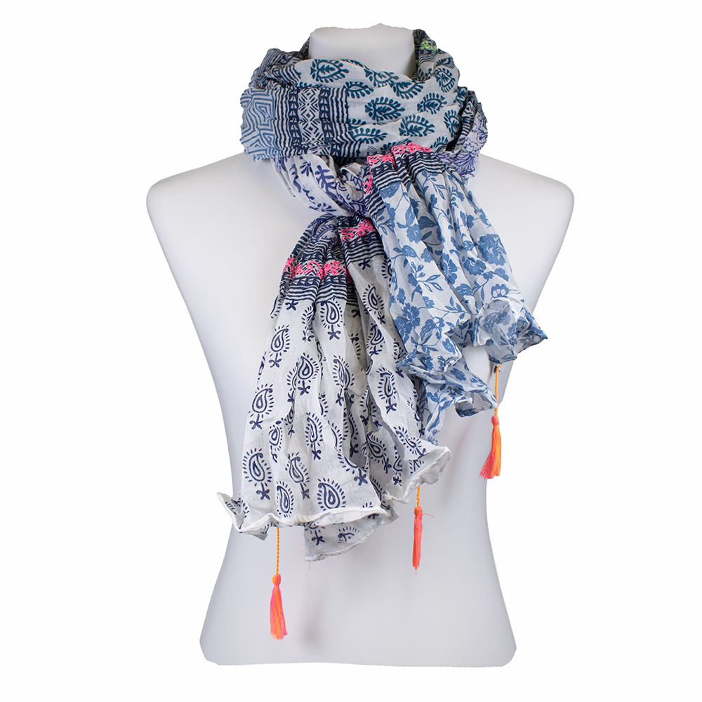 Blau-weißer Schal mit Mustermix aus floralen und geometrischen Elementen, umlaufenden Bordüren, feinen Neonakzenten und Quasten in Pink und Orange.