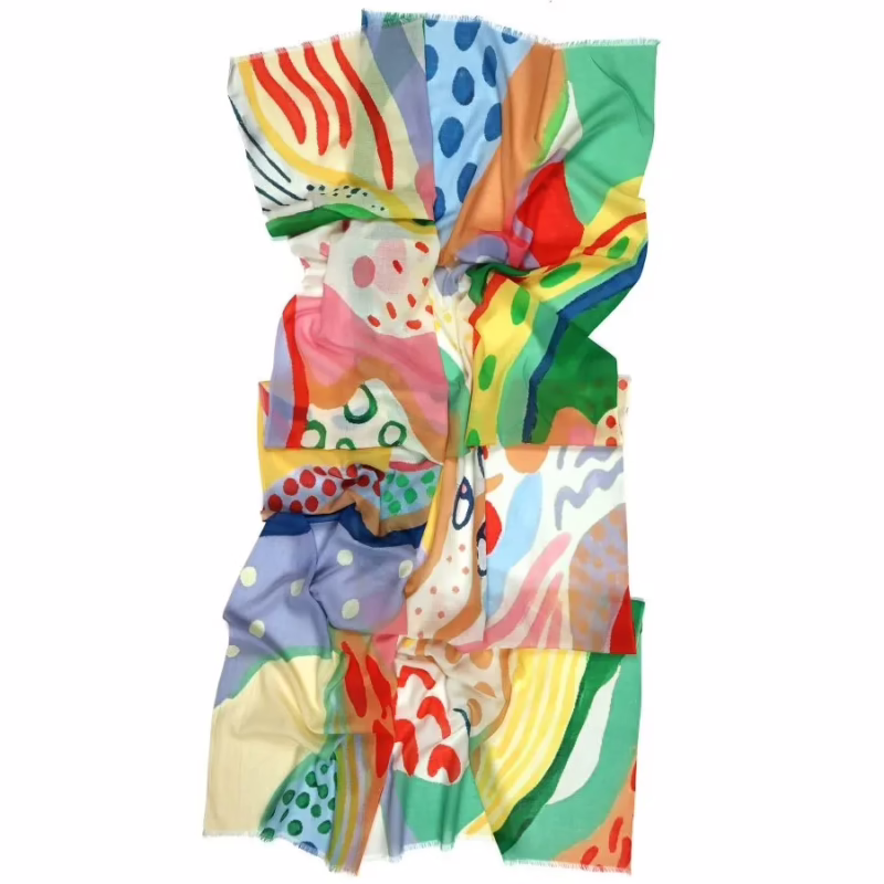 Detailaufnahme. Biobaumwollschal mit farbenfrohem, abstraktem Muster in Grün, Gelb, Rot und Blau, weich fallend und vielseitig tragbar.